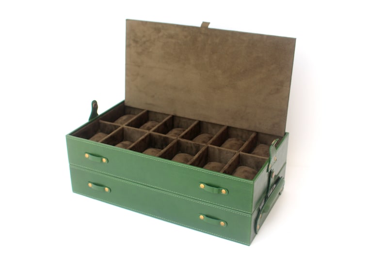 Puede incluir: Una caja rectangular verde para guardar relojes con tapa abatible y dos cajones. El interior est&aacute; forrado con tela marr&oacute;n y cuenta con doce compartimentos individuales, cada uno con una almohadilla para reloj de color marr&oacute;n.