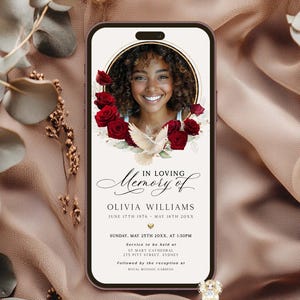 May include: A smartphone screen displays a memorial graphic. The design features a photo of a woman surrounded by red roses and a white dove. Text reads "In Loving Memory of Olivia Williams" with dates and service details.