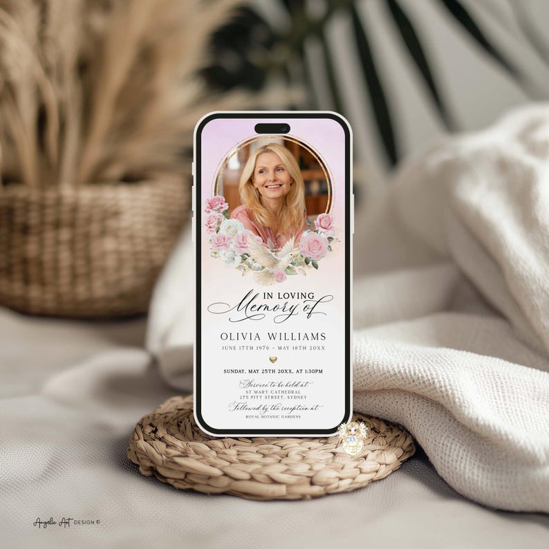 May include: A smartphone displays a memorial invitation. The screen features a photo of a woman surrounded by pink roses and doves. Text reads "In Loving Memory of Olivia Williams" with event details. The phone rests on a woven coaster.