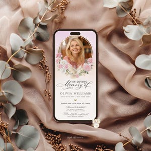 May include: A smartphone displays a memorial card with a photo of a woman, surrounded by floral and dove illustrations. The text reads "In Loving Memory of Olivia Williams" with dates and service details. The background is a soft, neutral color.