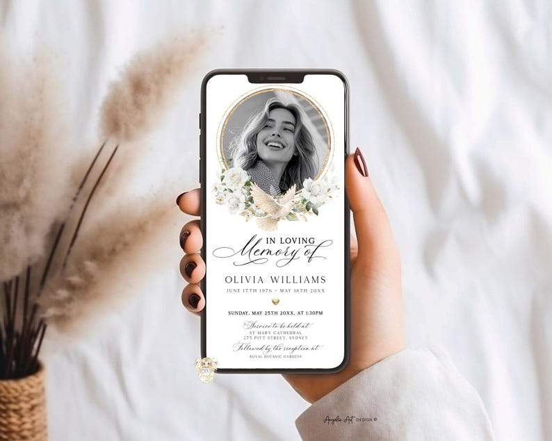 May include: A smartphone displays a memorial announcement. The design features a photo of a woman in a gold frame, surrounded by white flowers and a dove. Text includes "In Loving Memory of Olivia Williams" and event details.