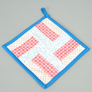 Könnte beinhalten: Ein blauer und weißer Patchwork-Topflappen mit einem karierten Muster. Der Topflappen ist aus Stoff und hat einen blauen Rand.