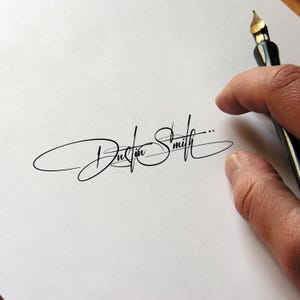 May include: A handwritten signature in black ink on white paper. The signature reads "Dustin Smith" in an elegant, cursive script. A black fountain pen is held in the upper right corner, with a hand partially visible.