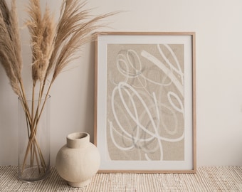May include: A framed abstract art print with a neutral color palette. The artwork features white, looping lines on a beige background. A clear glass vase with dried pampas grass and a small, cream-colored vase are in the foreground.