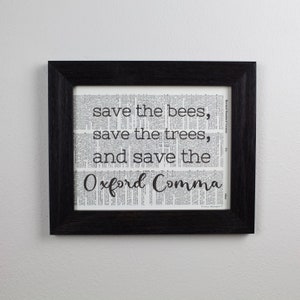 May include: A framed print with a black frame and a white background. The print features the text "save the bees, save the trees, and save the Oxford Comma".