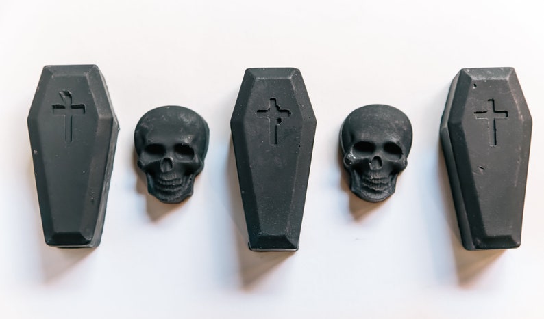 May include: Five black coffin-shaped soaps with a cross design and three black skull-shaped soaps.
