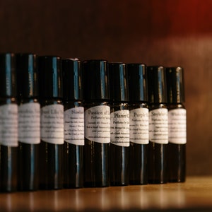 May include: A row of small, dark brown glass bottles with white labels. The labels have text that includes the words "Passion of Love" and "Planet C".