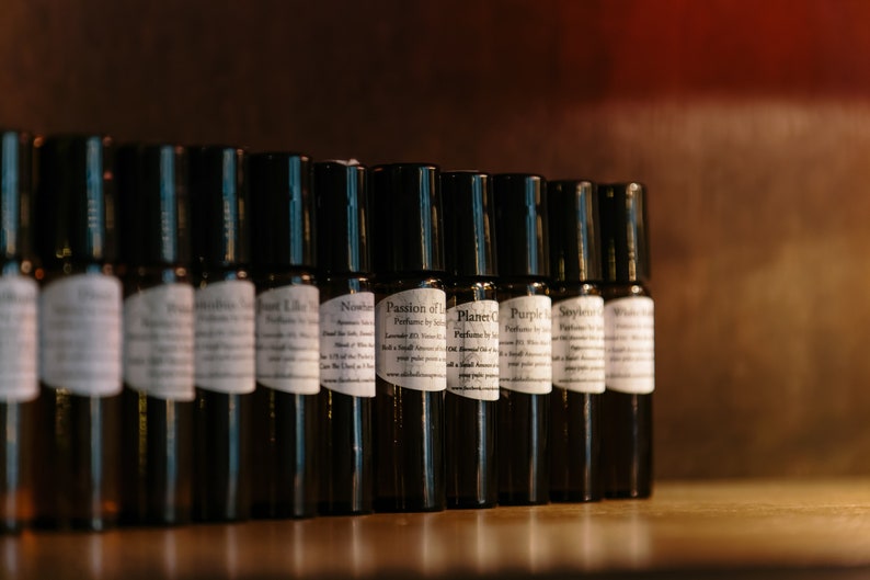 May include: A row of small, dark brown glass bottles with white labels. The labels have text that includes the words "Passion of Love" and "Planet C".