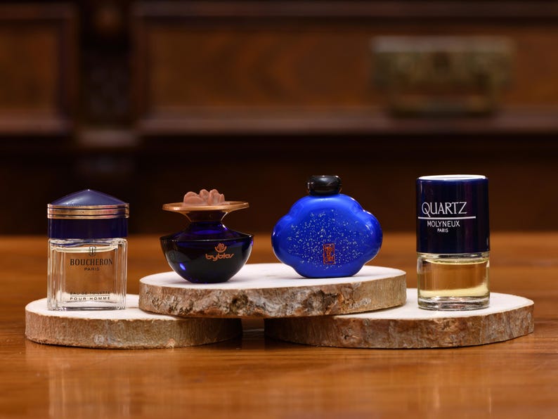 K&ouml;nnte beinhalten: Eine wei&szlig;e Keramik-Tasse mit schwarzem Henkel und dem Text "But First, Coffee" in fetter, schwarzer Schrift. Die Tasse steht vor einem neutralen Hintergrund, der ihr schlichtes Design hervorhebt.