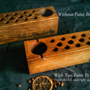 Pu&ograve; includere: Portapennelli in legno con fori multipli per pennelli. Un supporto ha due poggiapennelli. I testi "Julie's Brushes" e "Shannon" sono incisi sui supporti. Sono visibili anche i testi "Without Paint Brush Rests" e "With Two Paint Brush Rests".