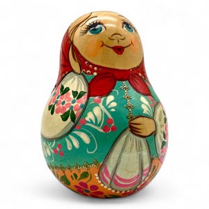 May include: A traditional Russian nesting doll, or matryoshka, painted with a colourful floral design. The doll is wearing a red headscarf and a blue and white dress.