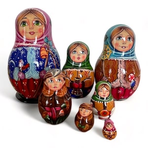 Può includere: Un set di sette bambole russe tradizionali, o bambole a incastro. Le bambole sono dipinte in uno stile di arte popolare colorato con scene invernali e personaggi. La bambola più grande indossa un vestito blu e rosso con una sciarpa bianca, e la bambola più piccola indossa un vestito rosa con una sciarpa bianca.