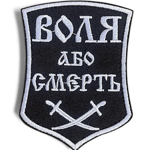 May include: A black embroidered patch in a shield shape with white stitching. The patch features the Cyrillic text "ВОЛЯ АБО СМЕРТЬ" and two crossed swords at the bottom. The border is white.