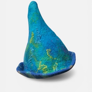 Peut inclure: Un chapeau en feutre bleu fait à la main, de forme conique et à large bord. Le chapeau présente un mélange de teintes turquoise et sarcelle, avec des accents brodés jaunes. Un accessoire unique.