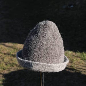 Peut inclure: Un chapeau en feutre gris à large bord. Le chapeau est en forme de cône et a une texture duveteuse.