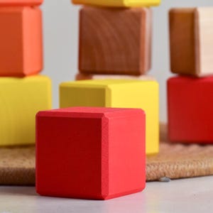 May include: A set of colorful wooden blocks in red, yellow, and orange. The blocks are stacked on top of each other, creating a tower.