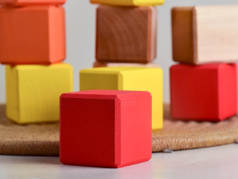 May include: A set of colorful wooden blocks in red, yellow, and orange. The blocks are stacked on top of each other, creating a tower.