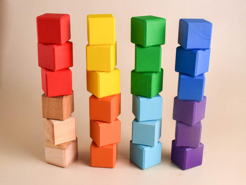 May include: A stack of colorful wooden blocks in red, yellow, green, blue, and purple. The blocks are arranged in a tower formation, with each color stacked on top of the other.