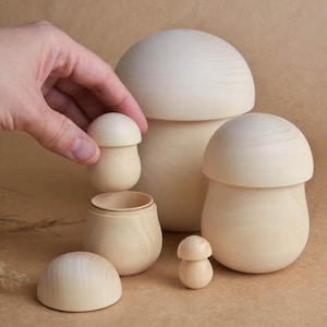 May include: Set of five wooden nesting mushrooms in various sizes. The mushrooms are all made of natural wood and have a smooth, light brown finish.
