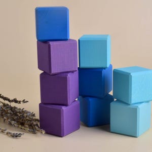 May include: A stack of wooden blocks in shades of blue and purple. The blocks are arranged in a staggered pattern, with the tallest stack on the left and the shortest stack on the right.