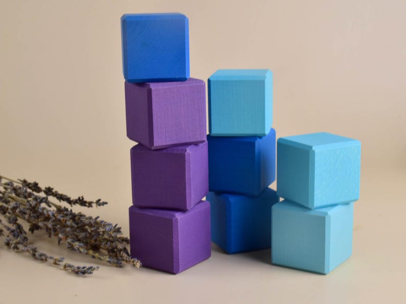 May include: A stack of wooden blocks in shades of blue and purple. The blocks are arranged in a staggered pattern, with the tallest stack on the left and the shortest stack on the right.