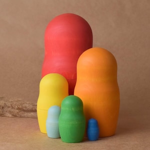 Könnte beinhalten: Ein Satz von sechs russischen Nistpuppen, auch bekannt als Matrjoschka-Puppen. Die Puppen sind in einem Regenbogenmuster bemalt, beginnend mit Rot, Orange, Gelb, Grün, Blau und Lila. Die größte Puppe ist rot, und die kleinste ist lila.