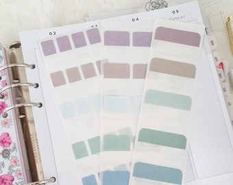 Pode incluir: Quatro folhas de adesivos transparentes para planejador com diferentes caixas retangulares coloridas. Os adesivos são etiquetados com os números 02, 03, 04 e 05. O adesivo etiquetado com o número 05 também tem a palavra "DOMINGO" impressa.