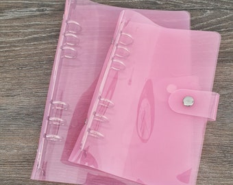 May include: Two pink transparent plastic binders with silver rings and a silver button closure.
