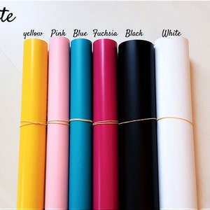 May include: Seven rolls of matte vinyl in various colors: yellow, pink, blue, fuchsia, black, and white. The rolls are tied with rubber bands.