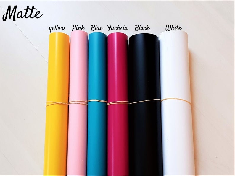 May include: Seven rolls of matte vinyl in various colors: yellow, pink, blue, fuchsia, black, and white. The rolls are tied with rubber bands.
