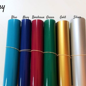 May include: Seven rolls of shiny vinyl in various colors: blue, navy, burgundy, green, gold, and silver. The rolls are wrapped with rubber bands.