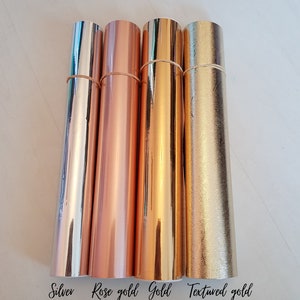 May include: Four rolls of metallic vinyl in silver, rose gold, gold, and textured gold. The rolls are labeled with the color names.