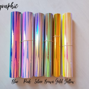 May include: Seven rolls of holographic vinyl in various colors, including blue, pink, silver, brown, gold, and yellow. The rolls are arranged horizontally, with the colors labeled below each roll.