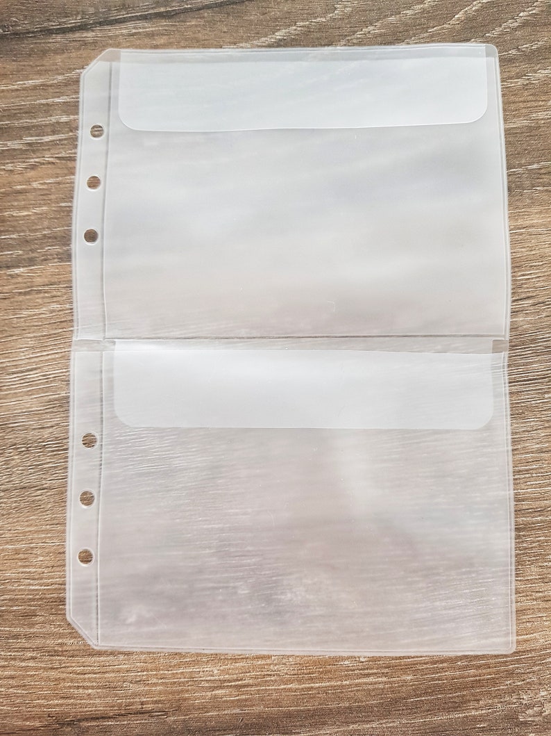 May include: Two clear plastic pockets with a flap closure and holes for a binder. The pockets are designed to hold papers or other small items.