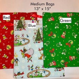 May include: Three medium-sized fabric bags, each approximately 13 x 15 inches. One is red with a Grinch-themed pattern, another is light blue with a Grinch scene, and the third is green with Christmas ornaments.