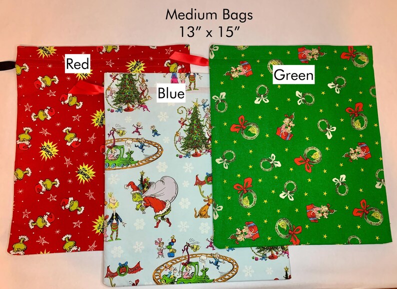 May include: Three medium-sized fabric bags, each approximately 13 x 15 inches. One is red with a Grinch-themed pattern, another is light blue with a Grinch scene, and the third is green with Christmas ornaments.