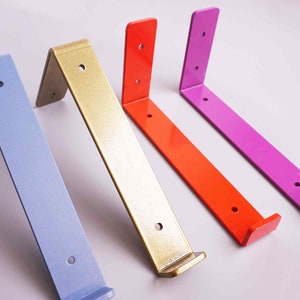 K&ouml;nnte beinhalten: Vier Metall-Regalb&ouml;cke in verschiedenen Farben: hellblau, gold, orange und lila. Jeder B&uuml;gel hat zwei L&ouml;cher zum Befestigen.
