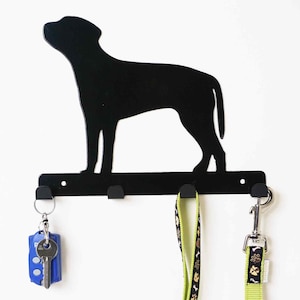 Könnte beinhalten: Schwarzer Metall-Schlüsselhaken in Form einer Hundesilhouette mit drei Haken. Eine grüne Leine und ein Schlüsselbund hängen an den Haken.