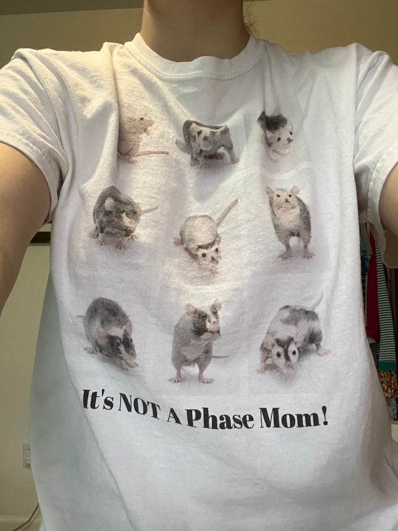 Pode incluir: Camiseta branca com um gr&aacute;fico de nove ratos em diferentes poses. O texto "It's NOT A Phase Mom!" &eacute; impresso abaixo dos ratos.