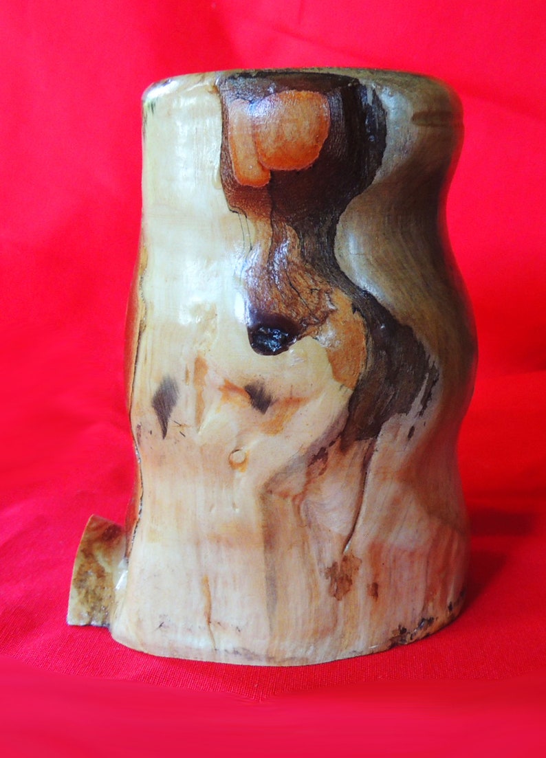 K&ouml;nnte beinhalten: Eine Holzevase mit nat&uuml;rlicher, rustikaler Oberfl&auml;che. Die Vase hat eine einzigartige, unregelm&auml;&szlig;ige Form und eine hellbraune Farbe mit dunkleren braunen Streifen.