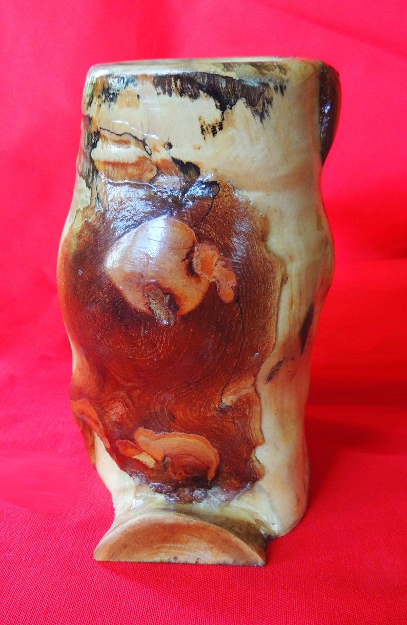 K&ouml;nnte beinhalten: Eine Holzvase mit einem nat&uuml;rlichen braunen und wei&szlig;en Holzmaserungsmuster. Die Vase hat eine einzigartige, organische Form und eine leicht ausgestellte &Ouml;ffnung.