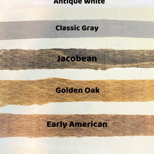 May include: Five wood stain samples on a white surface. The samples are labeled "Antique White", "Classic Gray", "Jacobean", "Golden Oak", and "Early American".