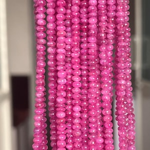 May include: Strands of vibrant pink gemstone beads. The beads are small, round, and uniform in size, creating a consistent texture. The color is a rich, saturated pink, and the beads are strung together, ready for jewelry making.