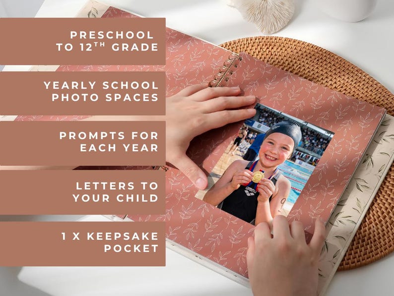 May include: A photo album with a pink cover featuring a leaf pattern. The album includes photo spaces, prompts, and a keepsake pocket. The image shows a child holding a medal. Text on the album reads: Preschool to 12th Grade.