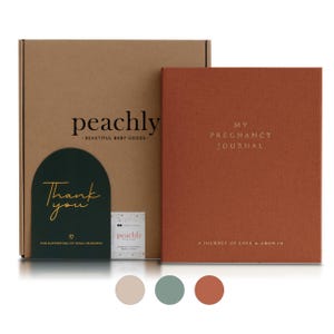 May include: A boxed set of baby goods, including a terracotta-colored pregnancy journal with gold lettering. The box is tan with the brand name "peachly" printed on it. A dark green card with gold text reads "Thank you".