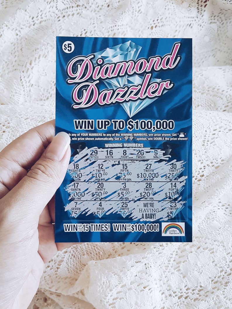 Pu&ograve; includere: Un biglietto della lotteria blu e rosa con le parole "Diamond Dazzler" e "Vinci fino a $ 100.000". Il biglietto ha un design a forma di diamante e un logo arcobaleno.