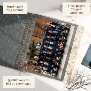 May include: Open spiral-bound photo album with a gold ring binding. The album features thick 200gsm cardstock pages and a gray cover with a leaf pattern. The album contains a group photo. Text on the album reads: "Quality you can feel on every page."