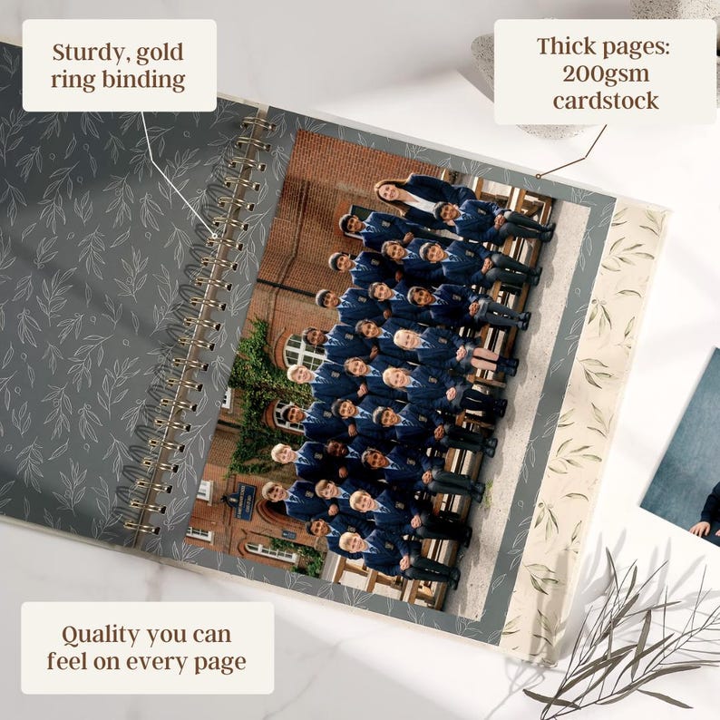 May include: Open spiral-bound photo album with a gold ring binding. The album features thick 200gsm cardstock pages and a gray cover with a leaf pattern. The album contains a group photo. Text on the album reads: "Quality you can feel on every page."