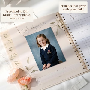 May include: A spiral-bound photo album with a picture of a young girl in a school uniform. The album is open to a page labeled "Kindergarten" with prompts and space for photos. Text on the album reads "Preschool to 12th Grade - every photo, every year."
