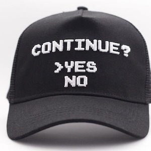 May include: Black trucker hat with white embroidered text that reads "CONTINUE? >YES NO"